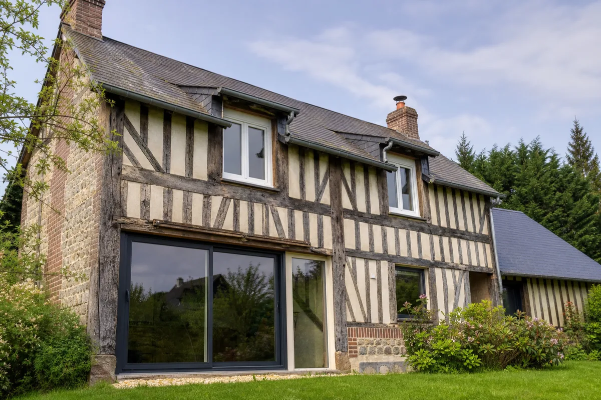 Fenêtres PVC blanches et baie aluminium anthracite sur une façade de maison normande