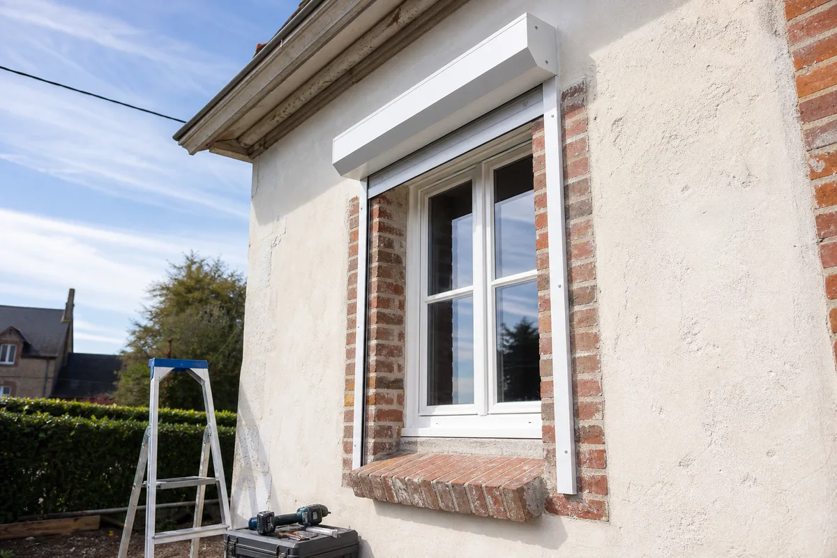 Volet roulant en applique posé au-dessus d’une fenêtre bois sur une façade normande